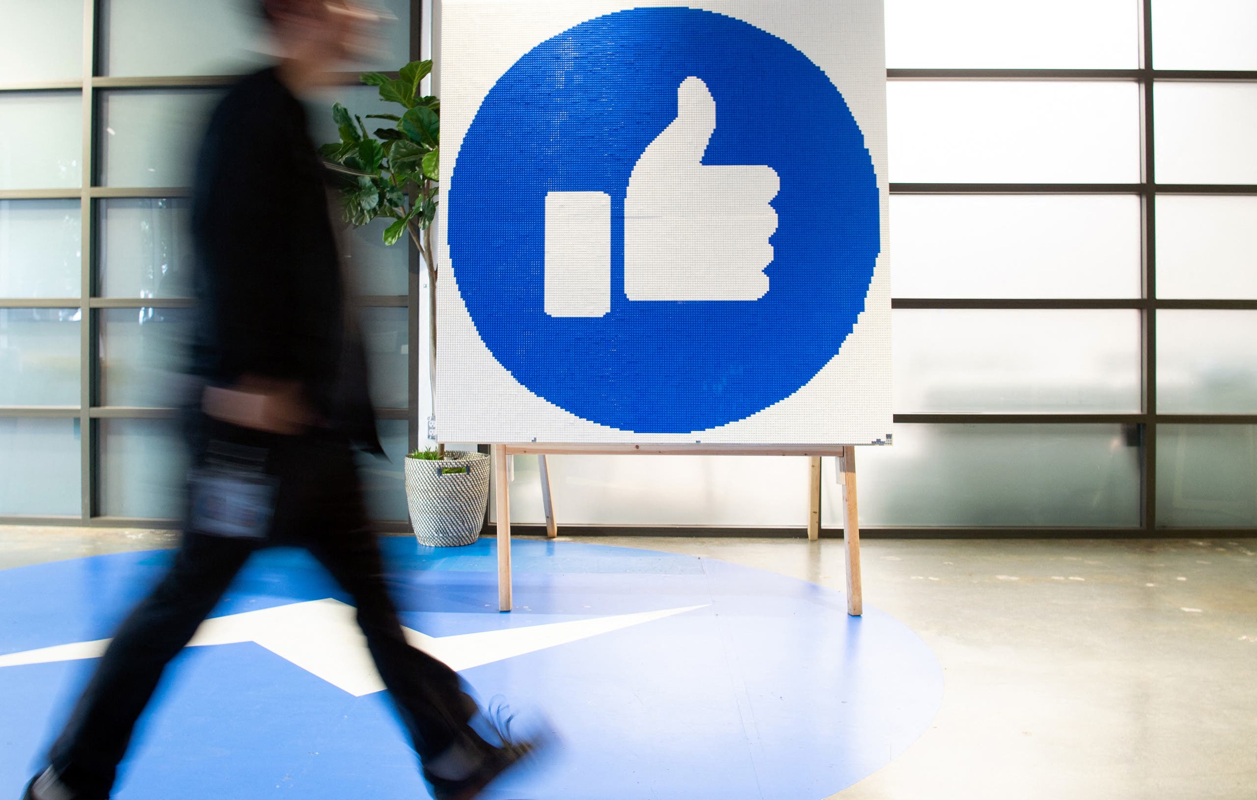 موظف في فيسبوك يمر أمام علامة إعجاب كبيرة في مقر الشركة في كاليفورنيا