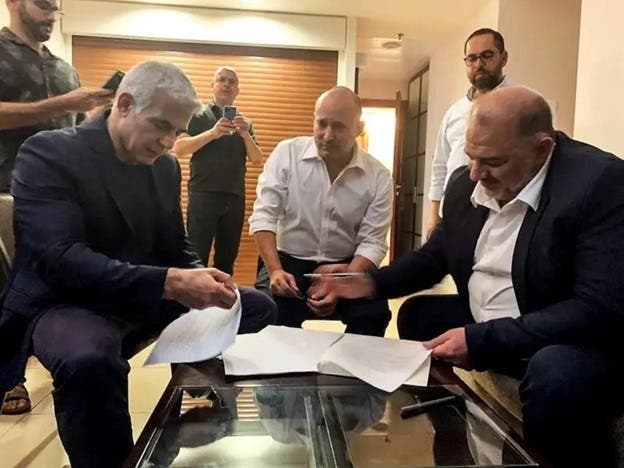صورة زعيم حزب القائمة العربية الموحدة منصور عباس وزعيم حزب يمينة نفتالي بينيت وزعيم حزب يش عتيد يائير لابيد، يجلسون معا في رمات غان ، بالقرب من تل أبيب